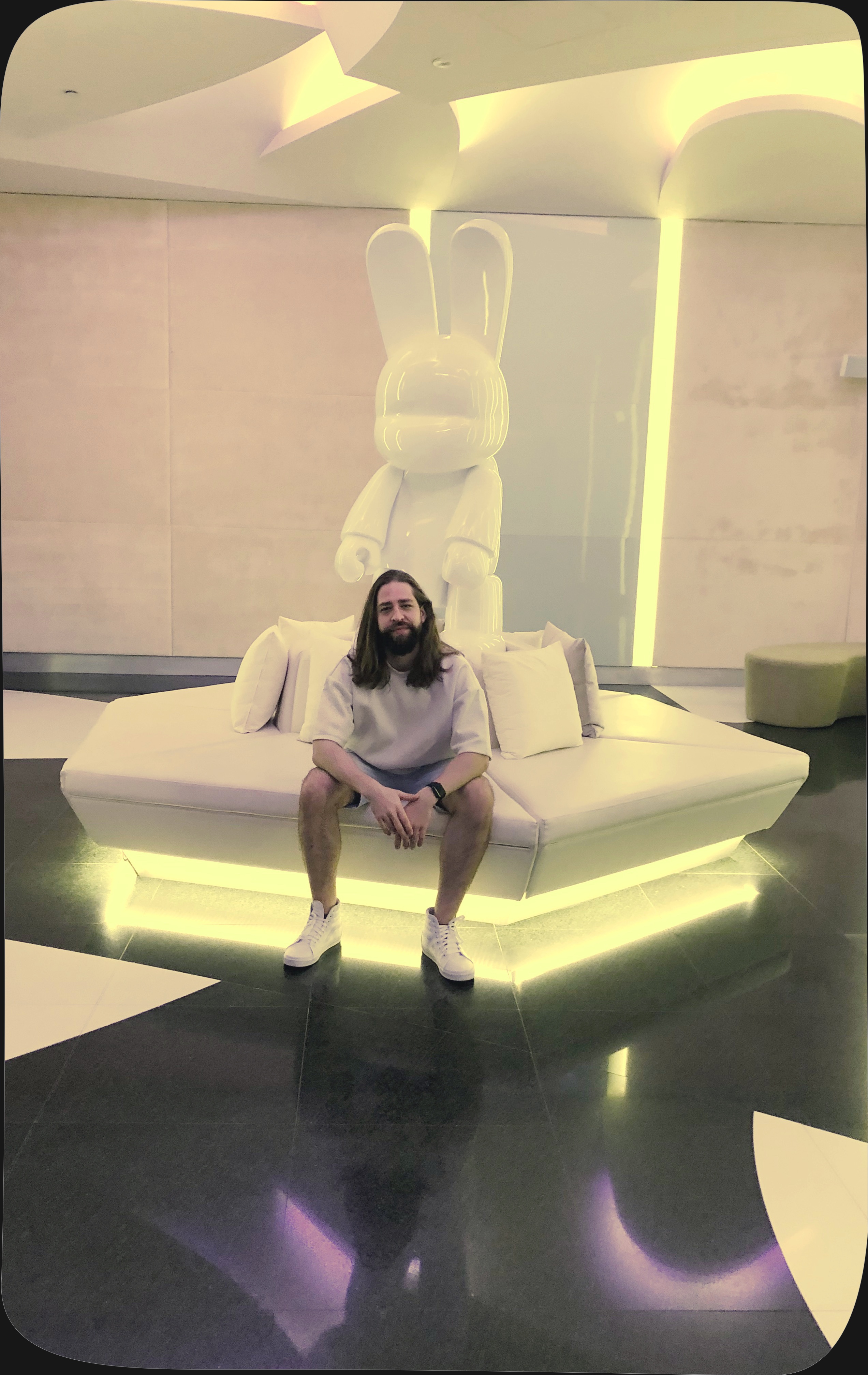 Adam sitting on a circular bench. A white bunny sculpture sits in the background.